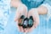 A pair of hands gently holds three small bottles of essential oils labeled 'Frankincense,' 'Lavender,' and 'Balance.' The background is a soft blue, matching the lace-trimmed sleeves of the person's clothing.