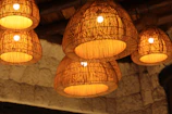 Pastoral woven wall lamp illuminating a textured wall with natural fibers and earth tones.