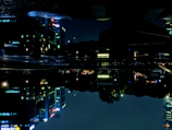 Um cenário urbano futurista com prédios altos e luzes neon refletindo na chuva.