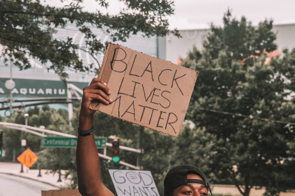 man holding brown and black wooden signage