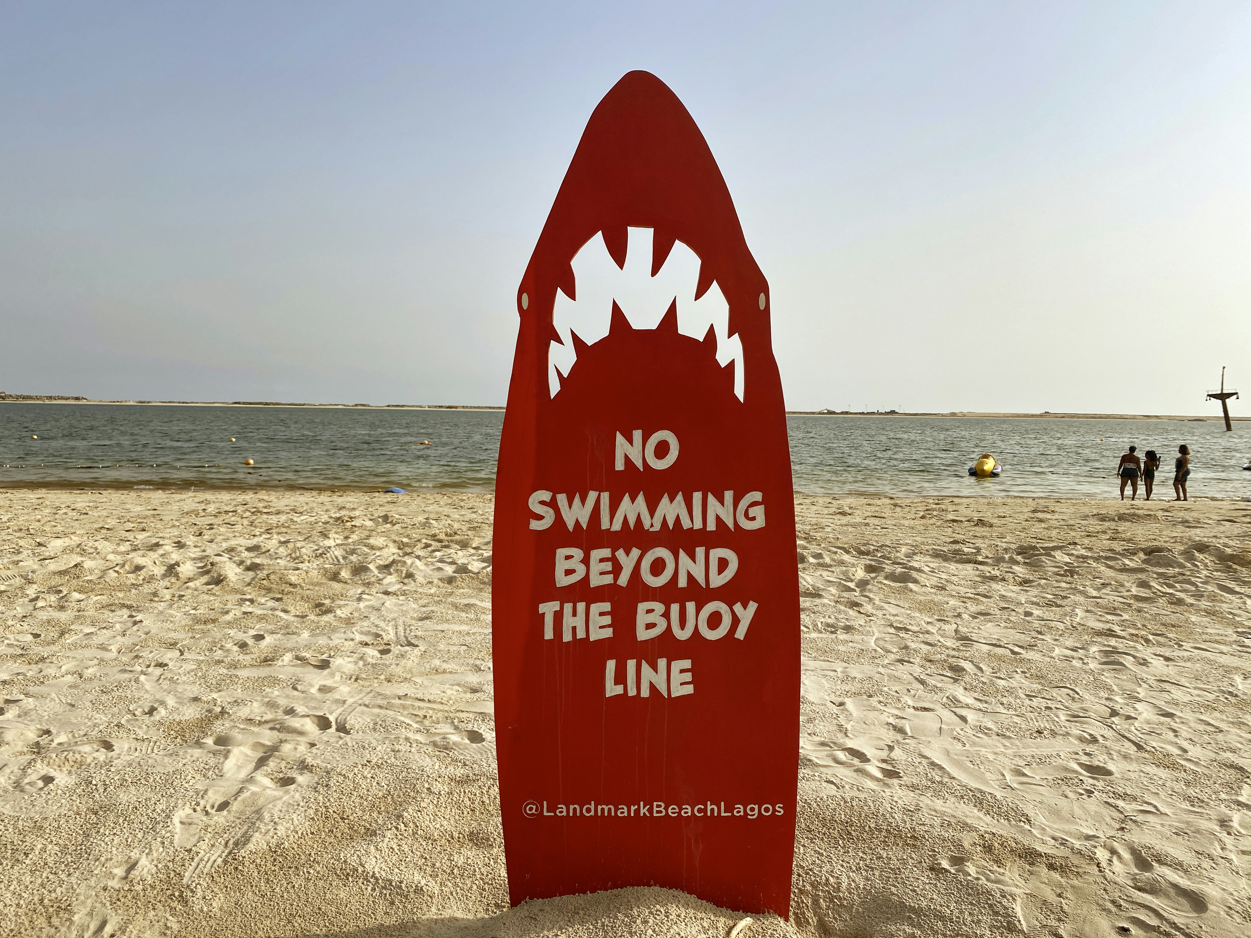 red and white beach signage on beach during daytime, 