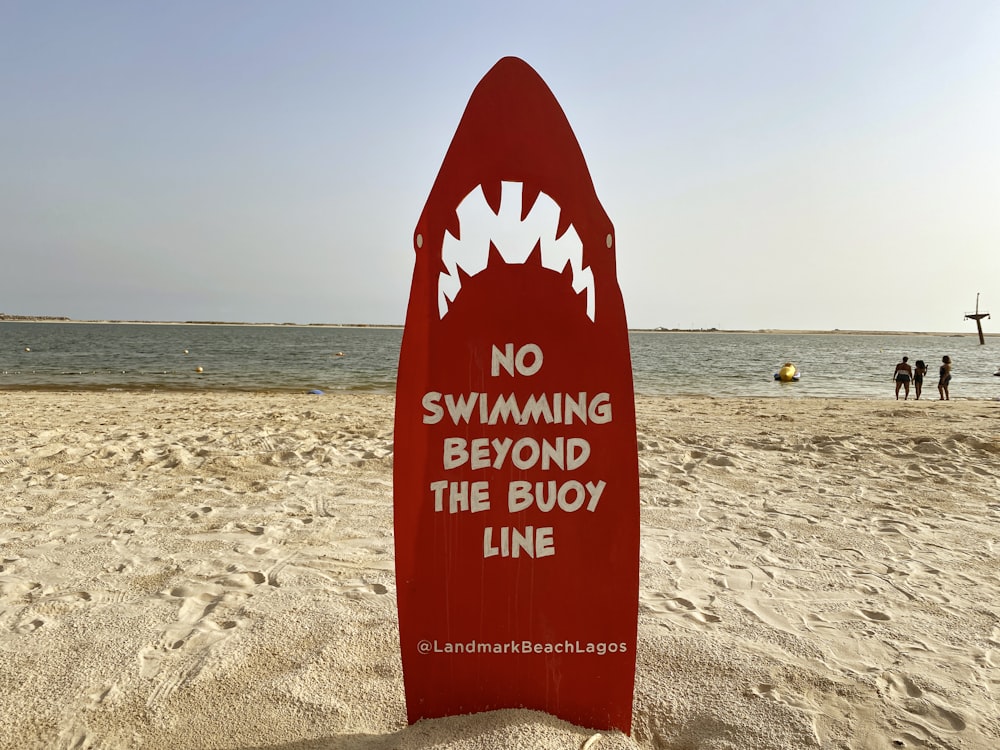 red and white beach signage on beach during daytime