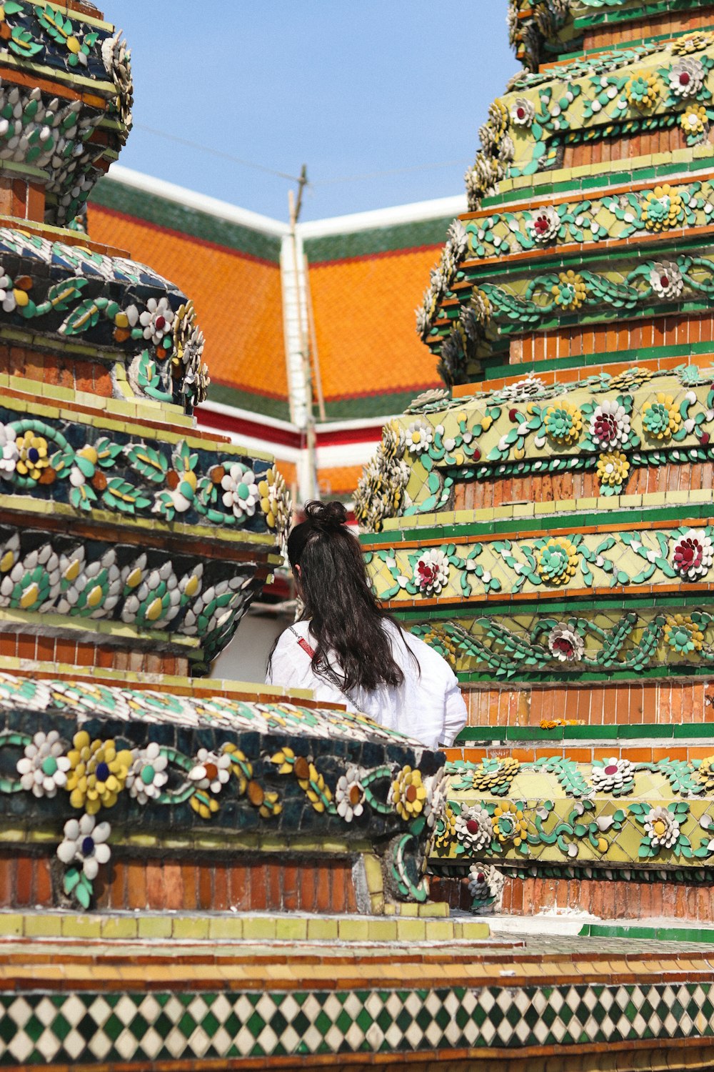 woman in white long sleeve shirt standing in front of temple during daytime