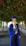 man in blue academic dress and academic hat standing near green tree during daytime