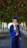 man in blue academic dress and academic hat standing near green tree during daytime