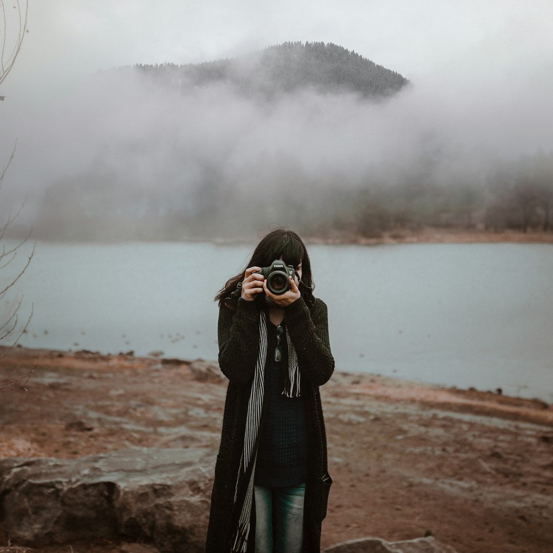 woman in black coat standing on brown field