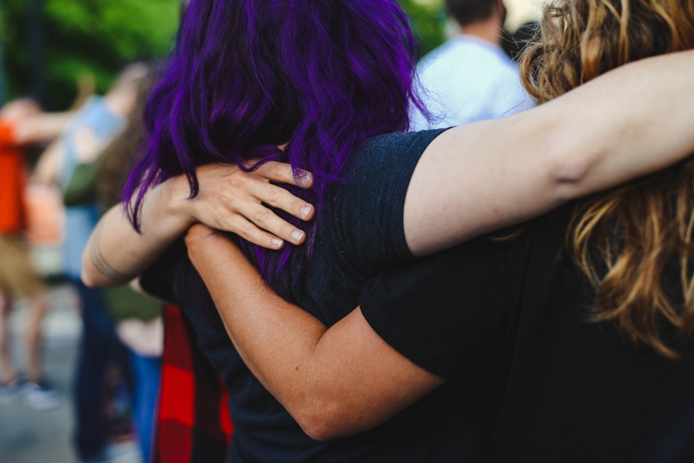 紫色の髪で顔を覆う黒いTシャツの女性