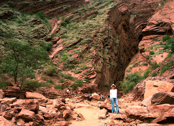 woman in blue shirt and blue denim jeans standing on brown rocky mountain during daytime