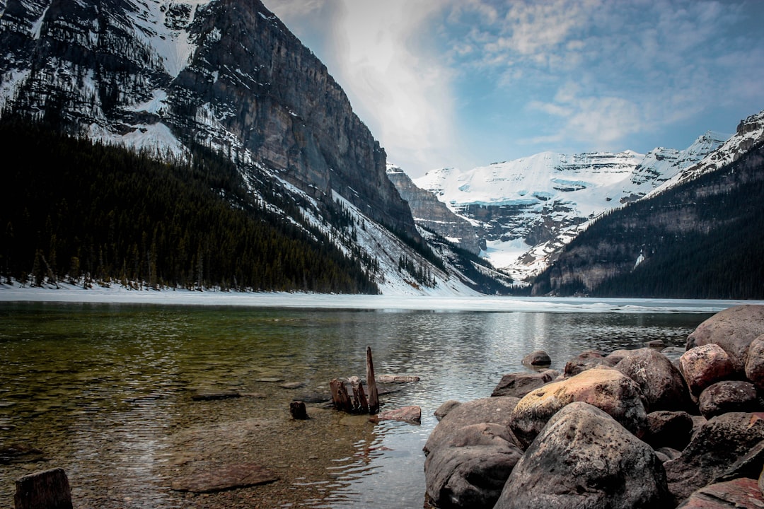 brown rocks on lake near snow covered mountain during daytime