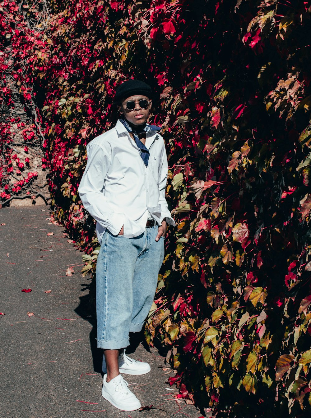 woman in white dress shirt and blue denim jeans standing on red leaves