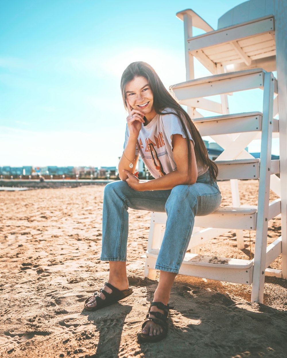 woman in gray t-shirt and blue denim jeans sitting on white wooden bench during daytime