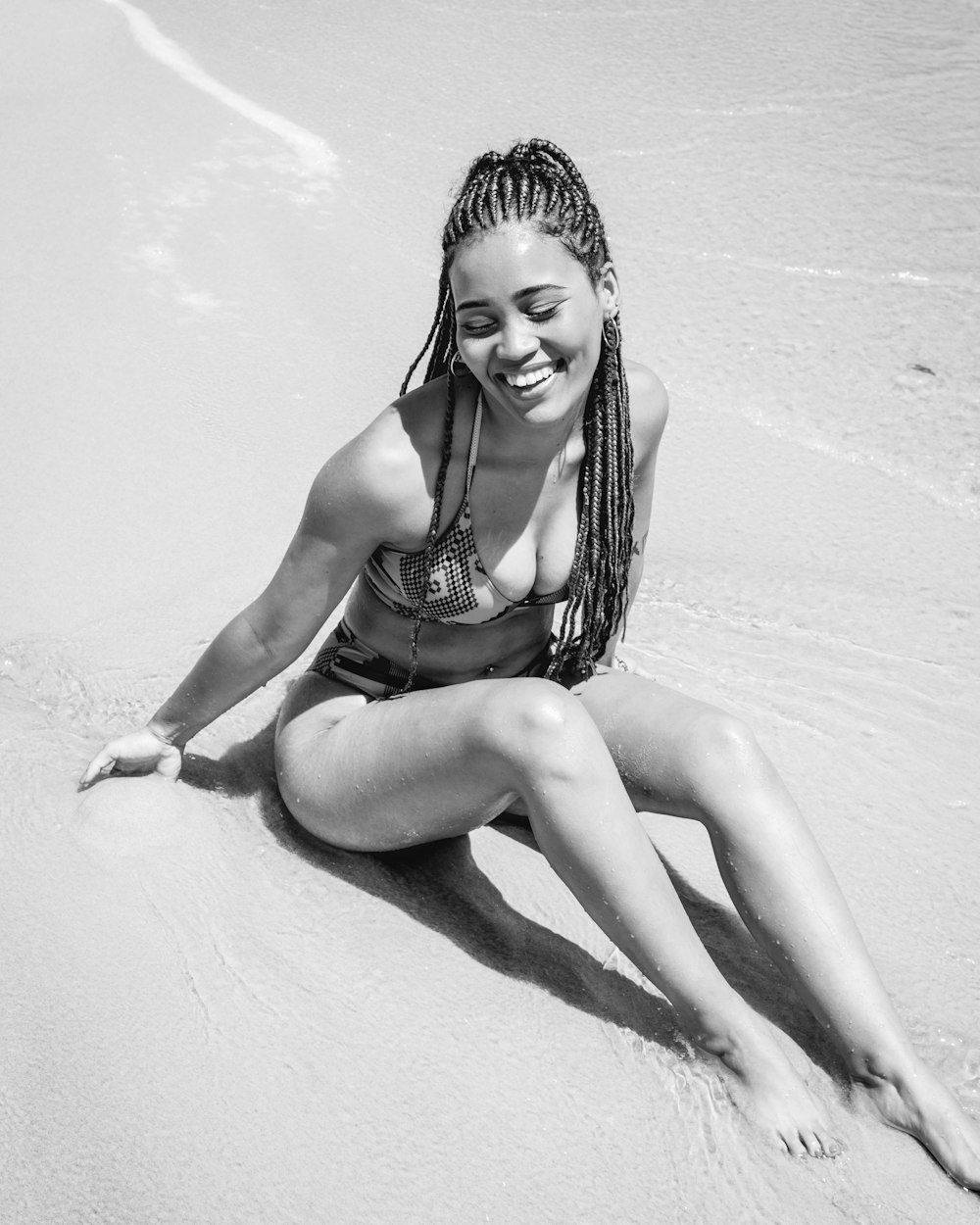woman in bikini sitting on sand