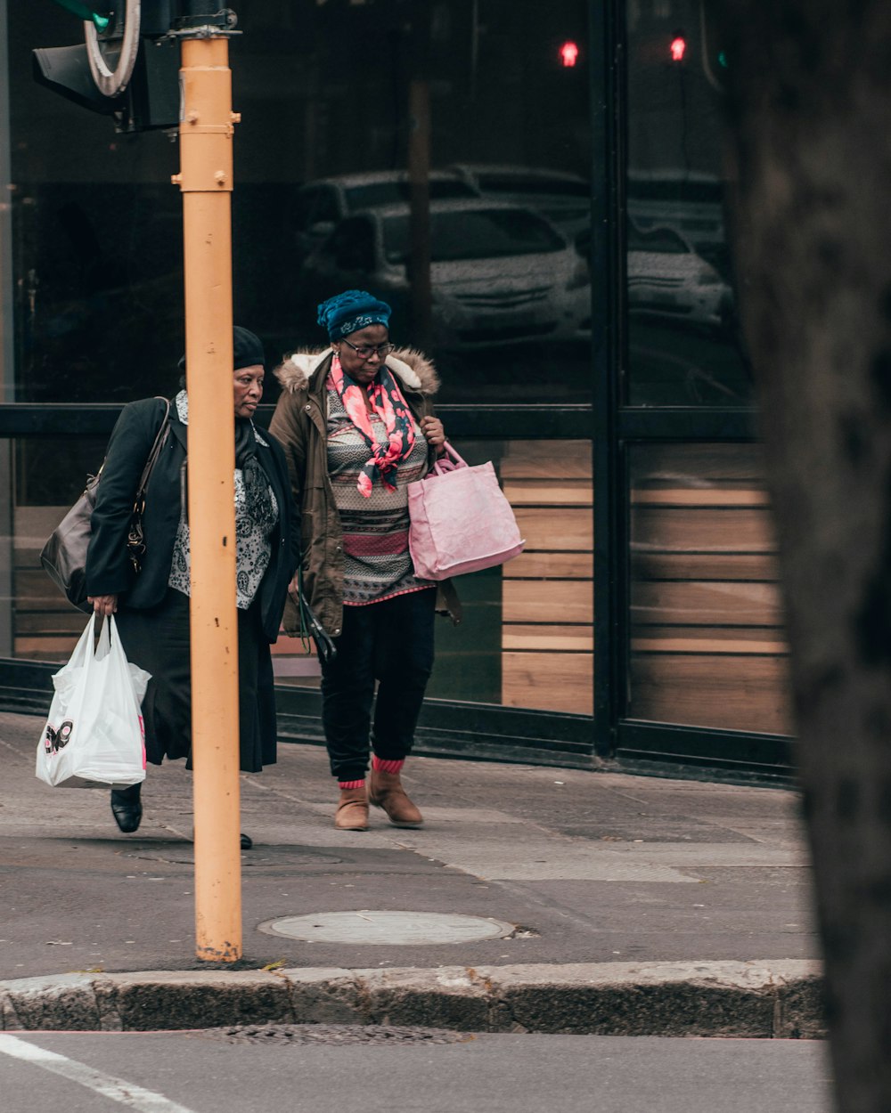 woman in black jacket and black pants carrying pink backpack walking on sidewalk during daytime