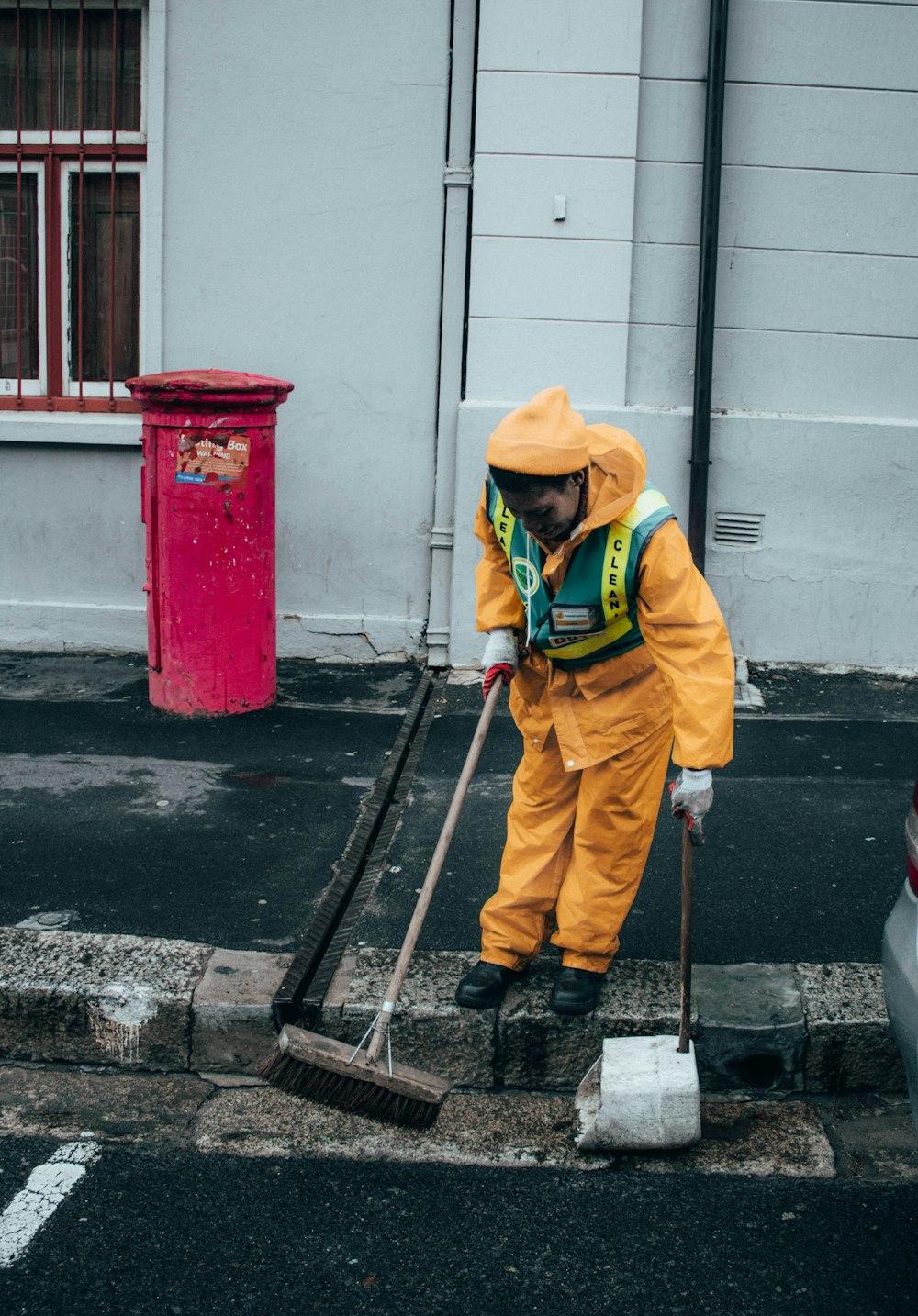 man in yellow jacket and orange hat holding black stick