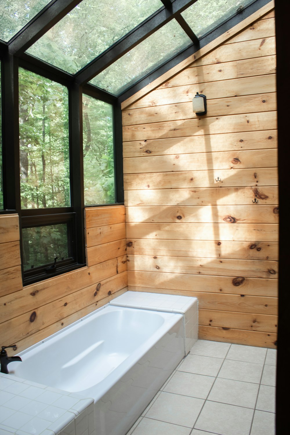 white ceramic bathtub near window