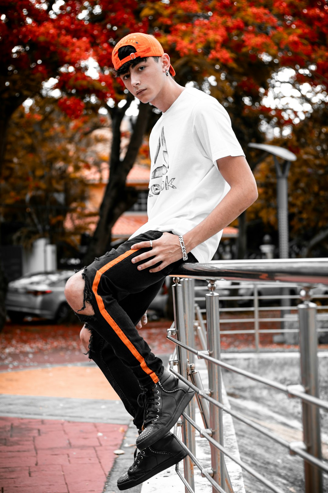 man in white crew neck t-shirt and black pants sitting on gray metal fence during