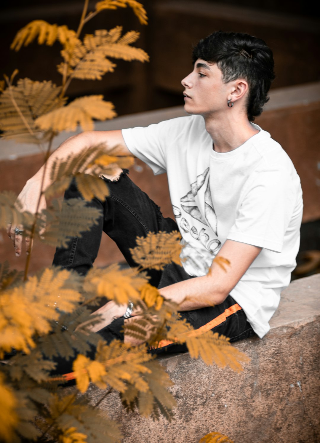 man in white crew neck t-shirt sitting on brown rock