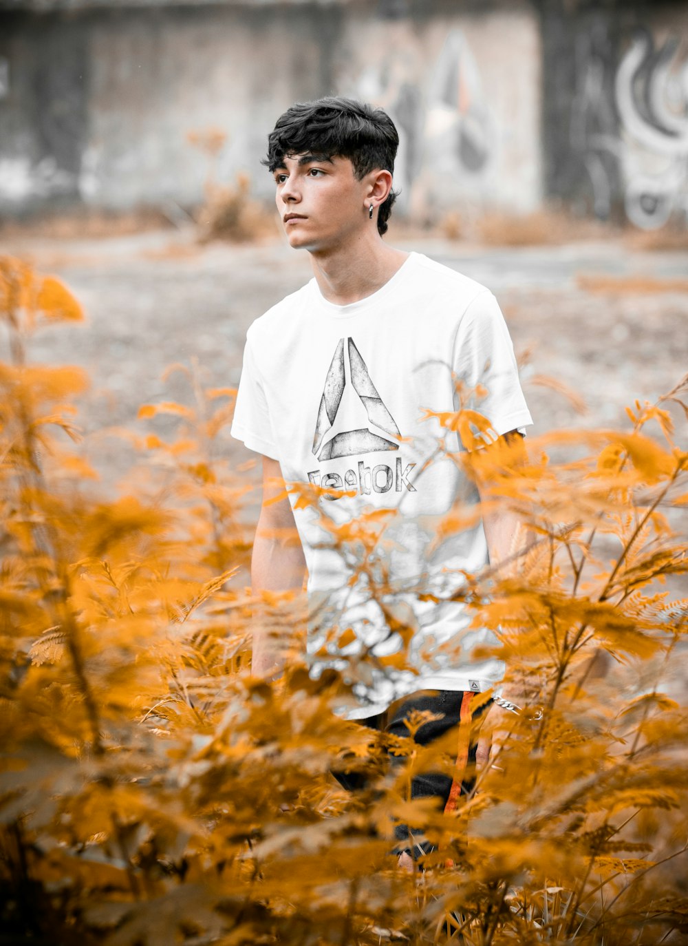 man in white crew neck t-shirt standing on brown grass field during daytime