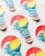 Several stickers shaped like light bulbs are arranged on a light surface. Each sticker features an artistic design of a wave overlaid on a sunset with vibrant colors. The top half showcases a red and yellow gradient resembling a sunset, while the bottom half displays a stylized blue wave.