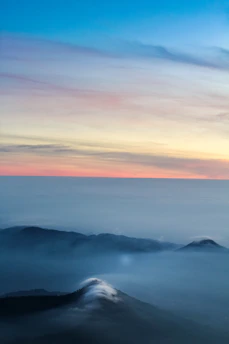 A serene sunrise over a misty mountain landscape with soft pastel colors.