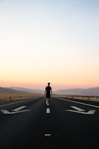 man in black jacket and black pants standing on black asphalt road during daytime