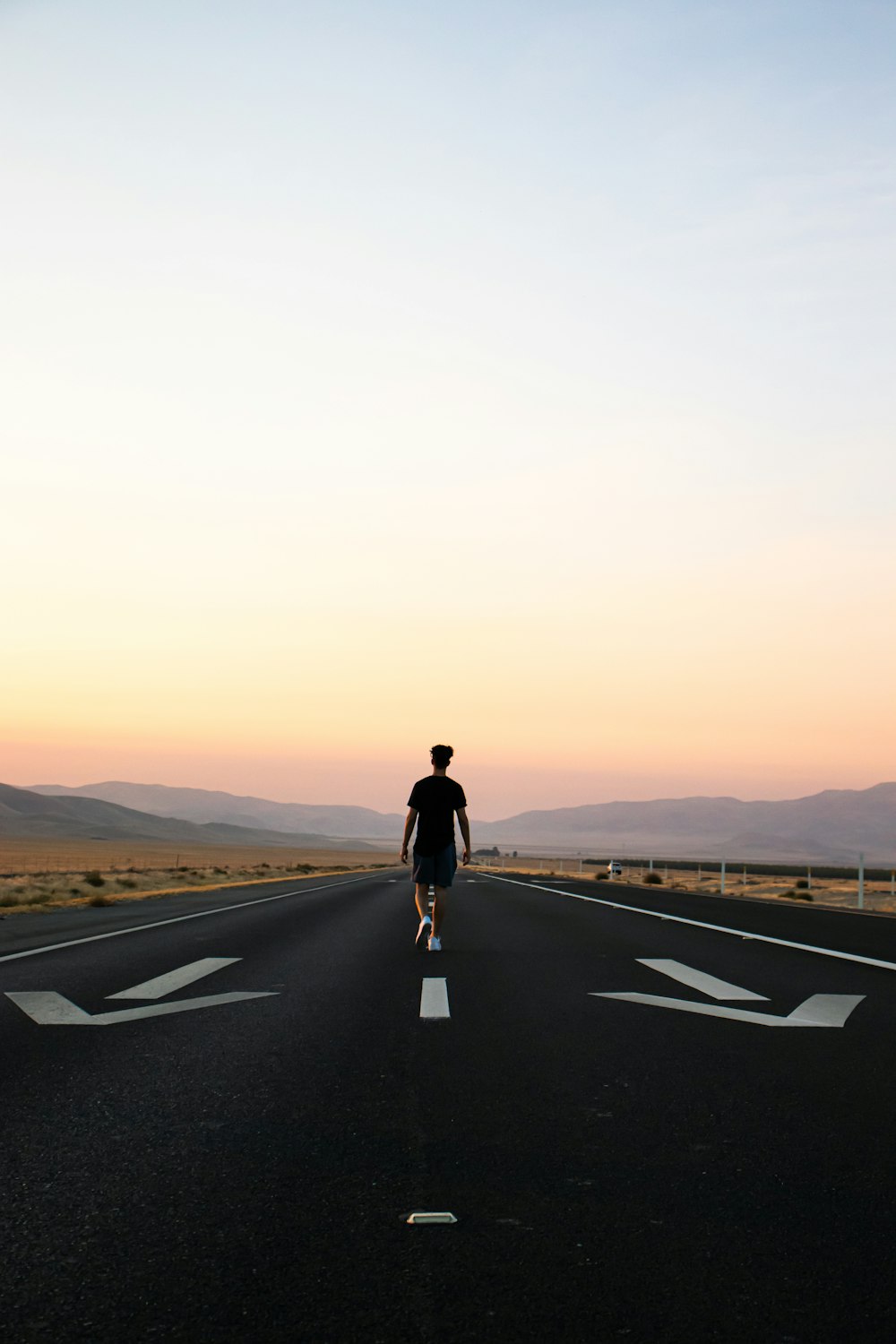 man in black jacket and black pants standing on black asphalt road during daytime