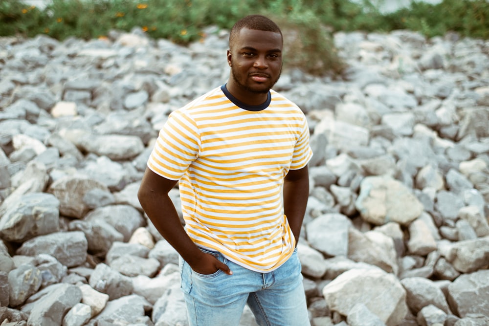 man in yellow and white striped crew neck t-shirt standing near green trees during daytime