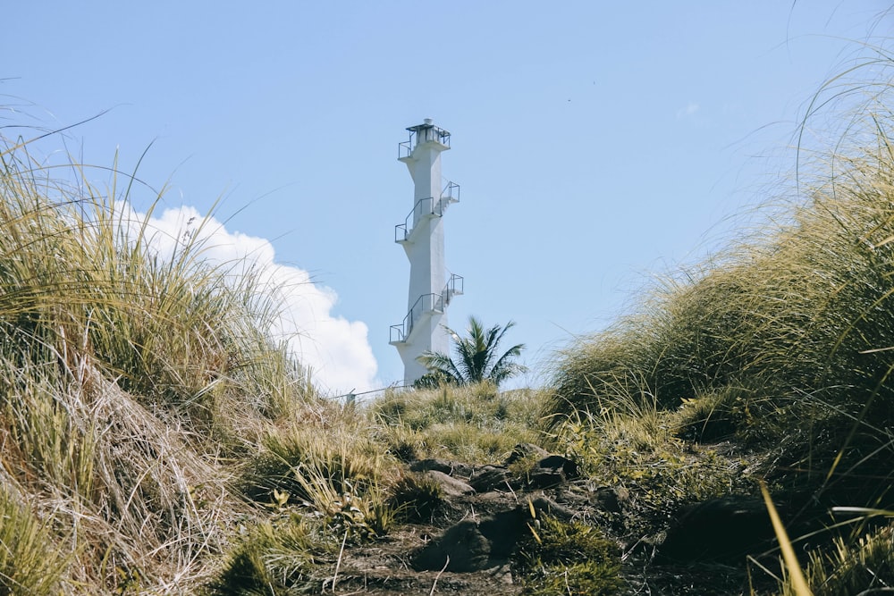 white concrete tower on brown rocky ground under blue sky during daytime