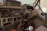 The interior of an old, dusty Land Cruiser with a worn out dashboard. It features a steering wheel, various dashboard controls and gauges, a radio, and old communication equipment. The seats show signs of wear and the general aesthetic is rugged and utilitarian, indicative of an older model vehicle.