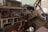 The interior of an old, dusty Land Cruiser with a worn out dashboard. It features a steering wheel, various dashboard controls and gauges, a radio, and old communication equipment. The seats show signs of wear and the general aesthetic is rugged and utilitarian, indicative of an older model vehicle.