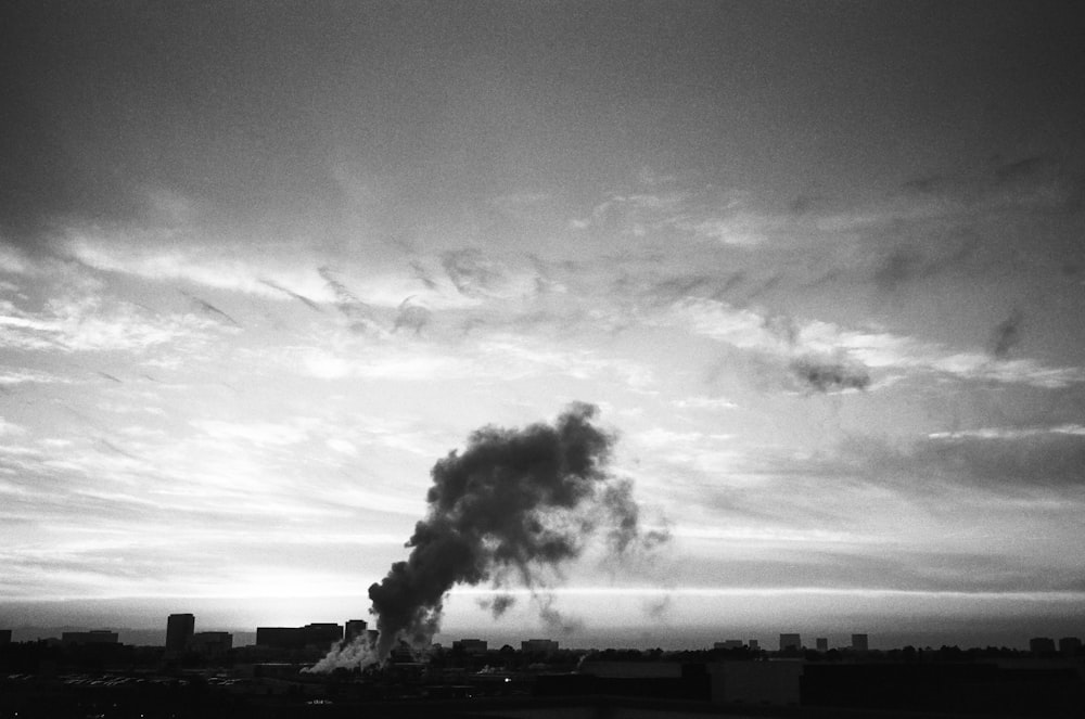 grayscale photo of smoke coming from factory