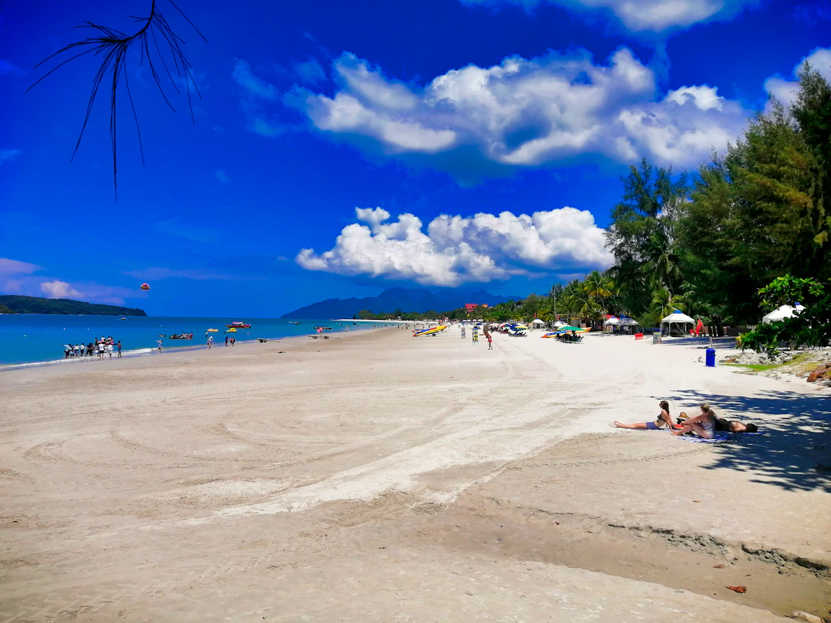 Visitors enjoying a white sand beach on Langkawi island