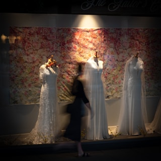 homme et femme en robe de mariée debout à côté d'un rideau floral blanc