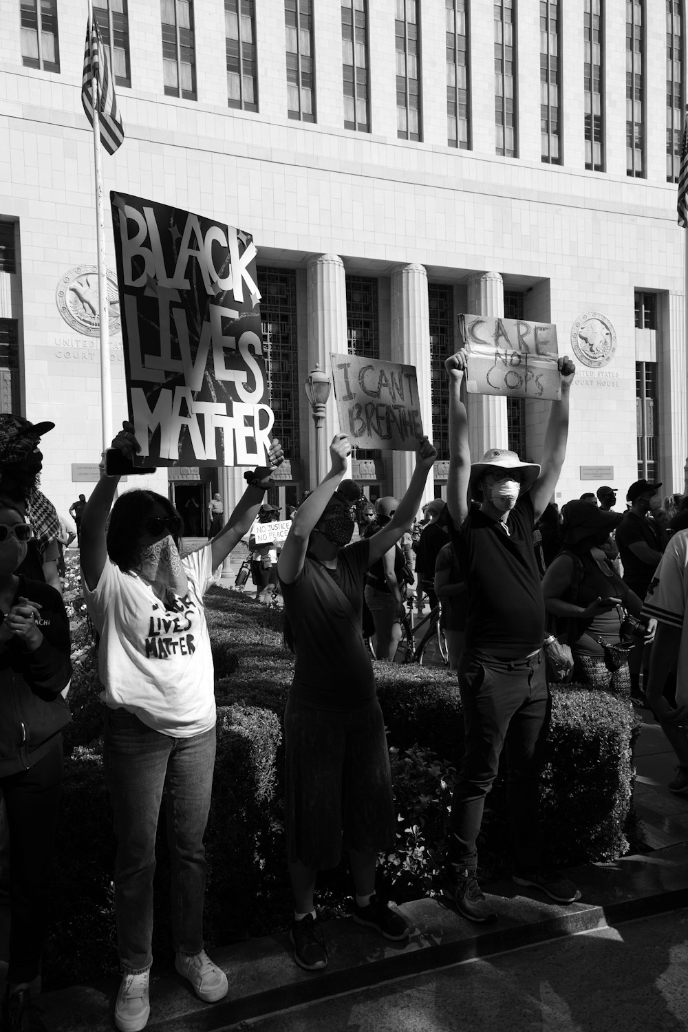 grayscale photo of people in front of white and gray building