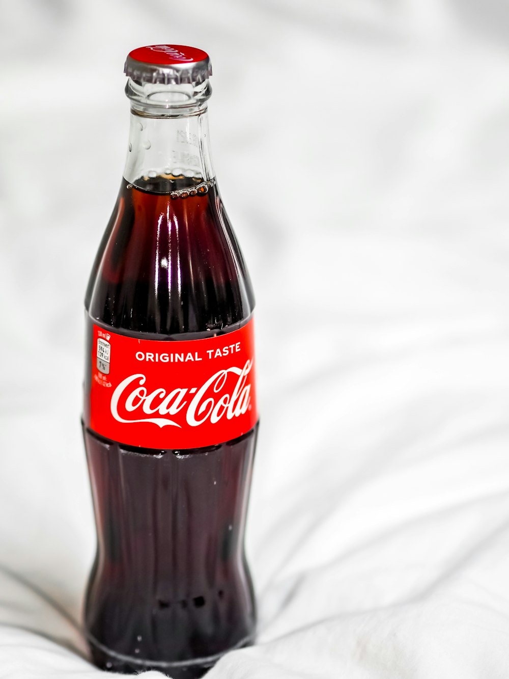 coca cola glass bottle on white textile