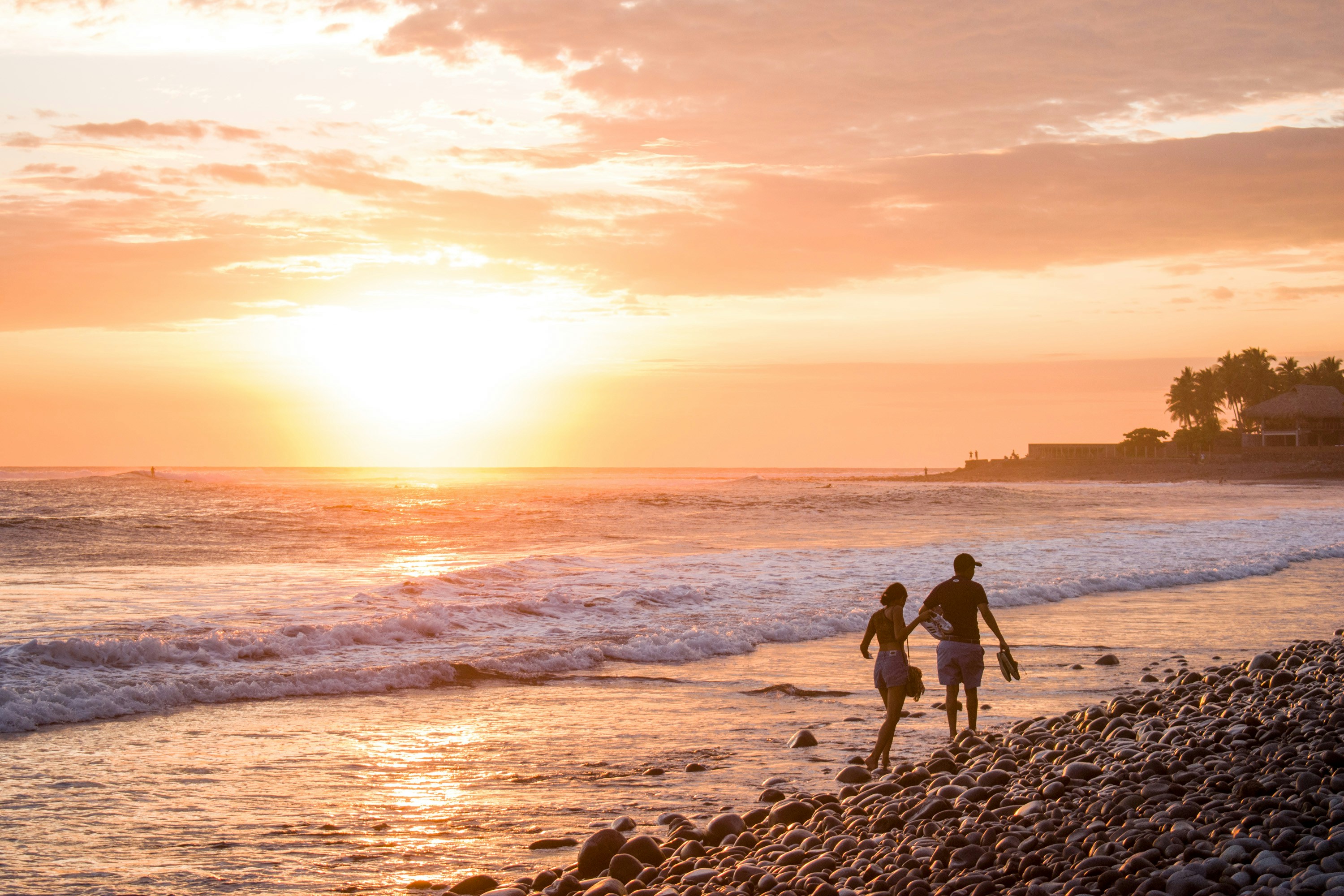 Silhouette von 2 Personen, die bei Sonnenuntergang am Strand stehen