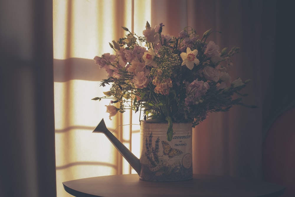 pink flowers in white ceramic vase on brown wooden table