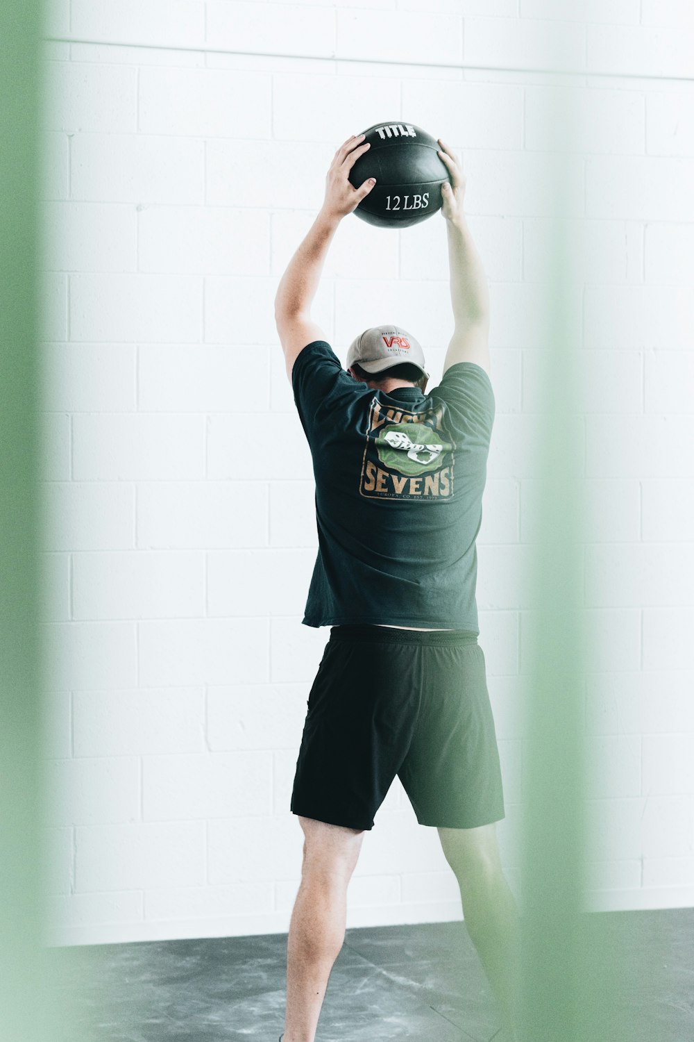 Mann in grünem Rundhals-T-Shirt und schwarzen Shorts mit schwarz-weißem Basketball