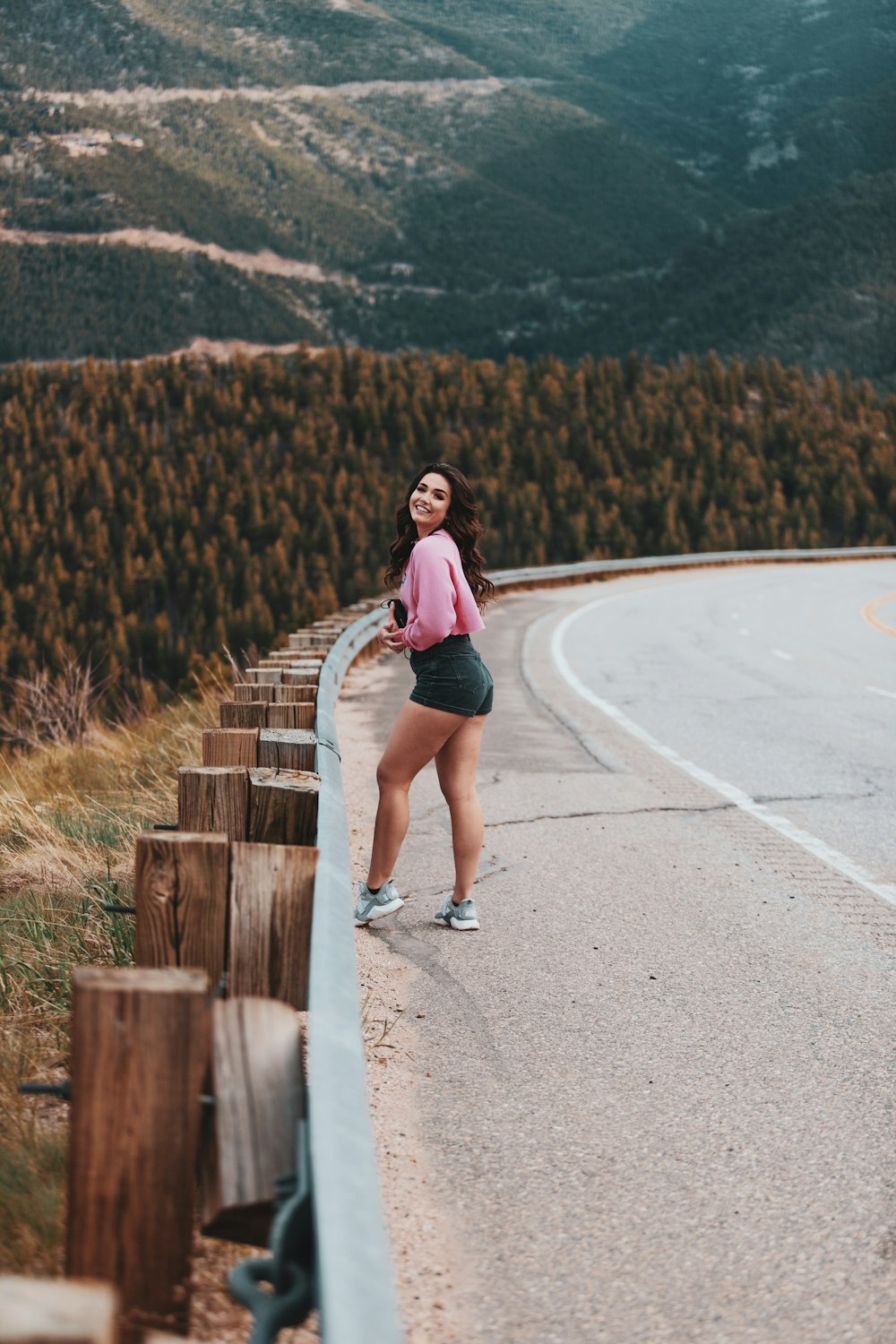 woman in purple long sleeve shirt and blue denim shorts walking on gray asphalt road during