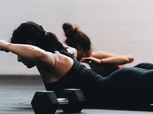 woman in black tank top and black leggings lying on black floor