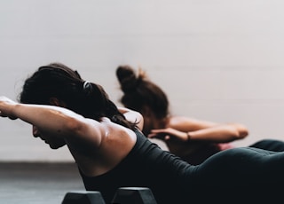 woman in black tank top and black leggings lying on black floor