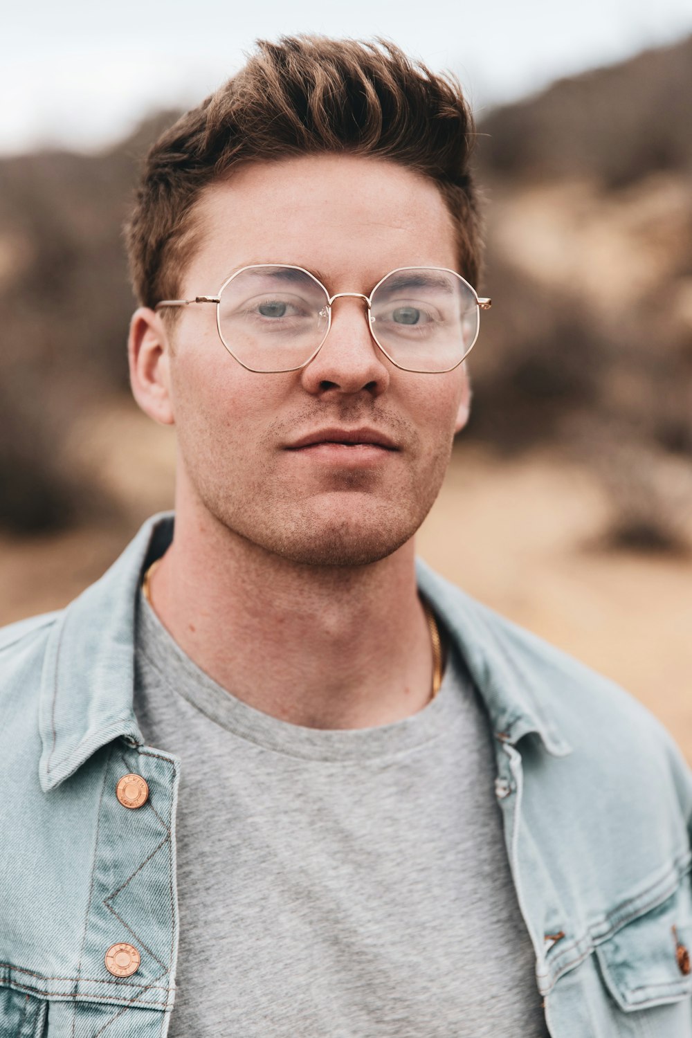 man in blue denim button up jacket wearing black framed eyeglasses