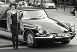 An influencer capturing content beside a classic car.