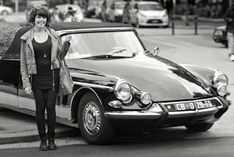 Smiling young woman holding a voucher in front of a modern driving school car.