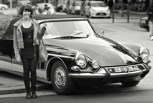 Smiling young woman holding a voucher in front of a modern driving school car.
