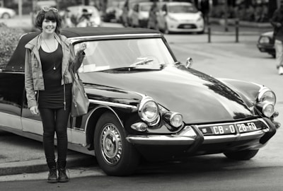 An influencer capturing content beside a classic car.