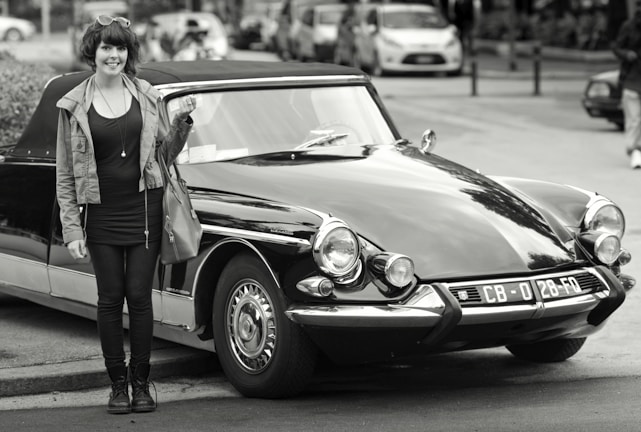 Happy young woman holding her new driver's license in front of a car at CFC Auto Escola Clima.