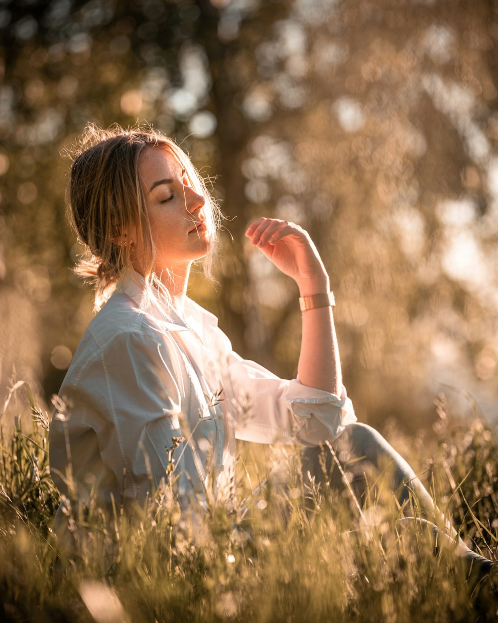 donna in vestito bianco che si siede sull'erba marrone durante il giorno