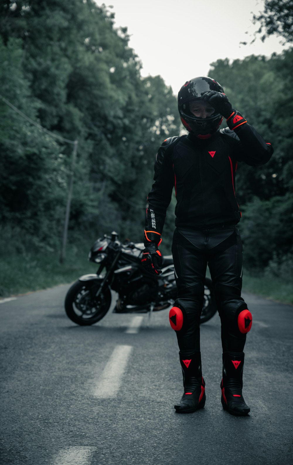 검은 재킷과 검은 바지를 입은 남자가 검은 오토바이를 타고