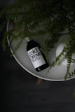 Sleek bottled cold-brew milk tea with condensation droplets, placed on a wooden table near a sunny window